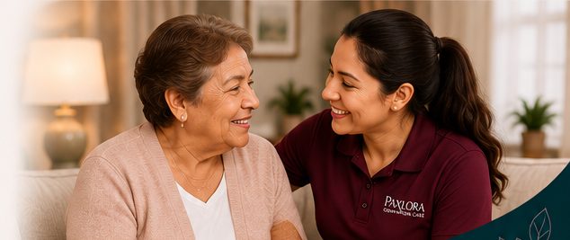 A caregiver and older woman sharing a warm conversation on a sofa