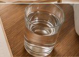 A glass of water on a wooden table, part of a daily hydration routine